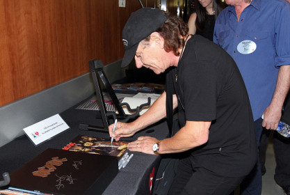 Brian Johnson assinante alguns itens da banda para o leilão de caridade do Grammy (07/02/2015)