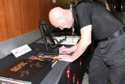 Chris Slade assinante alguns itens da banda para o leilão de caridade do Grammy (07/02/2015)